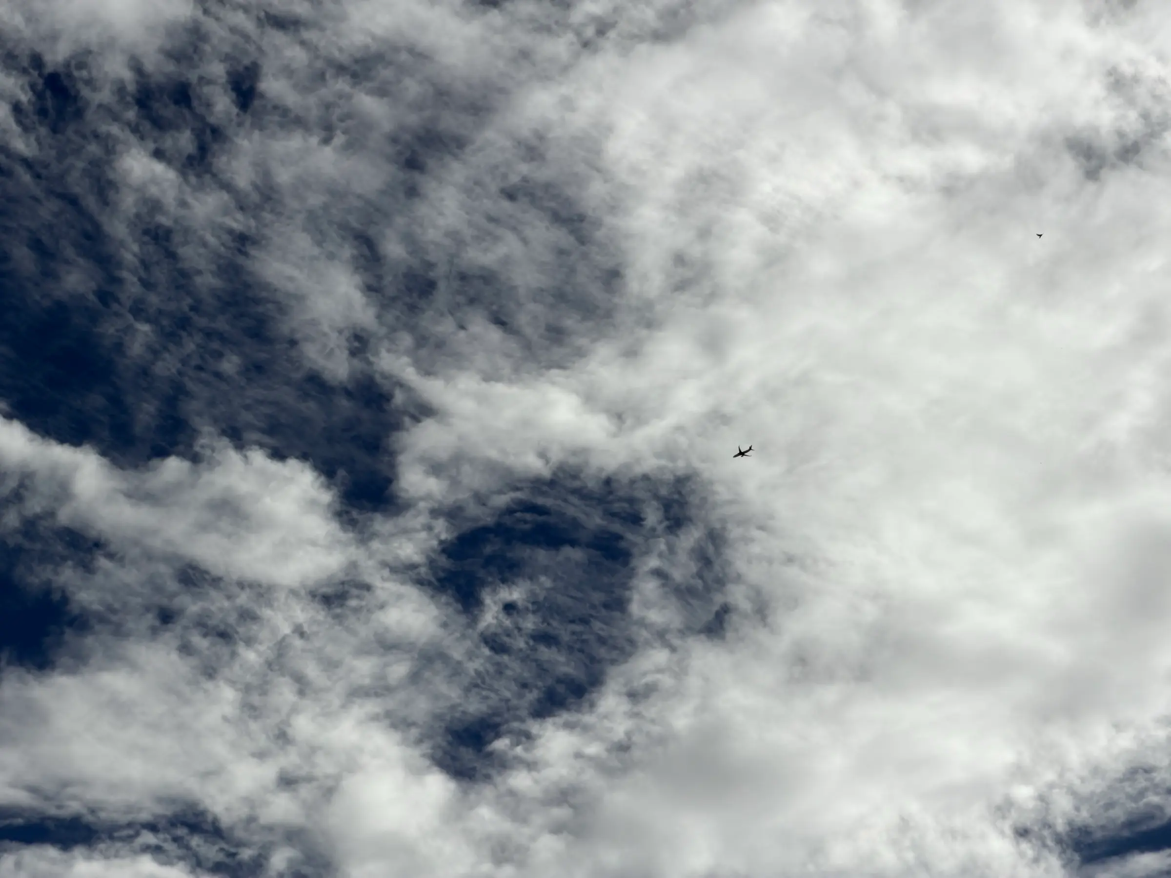 A plane crossing a break in heavy clouds